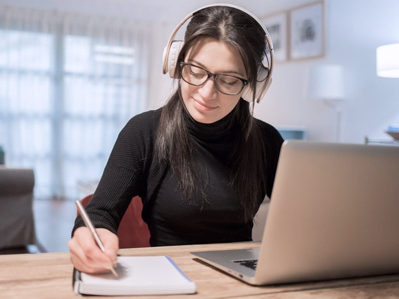 Woman working from home on her laptop with headset on.